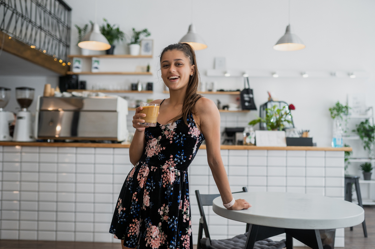 Woman holding an iced coffee in a bright café